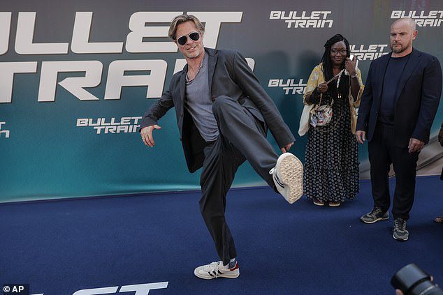 CATCHING: Movie star Brad donned a pair of comfy white trainers as he raised his leg toward the paparazzi as he walked the blue carpet