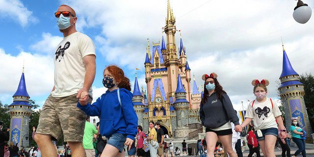 A masked family walks near Cinderella's Castle in the Magic Kingdom, at Walt Disney World in Lake Buena Vista, Florida, on Monday, December 21, 2020. 